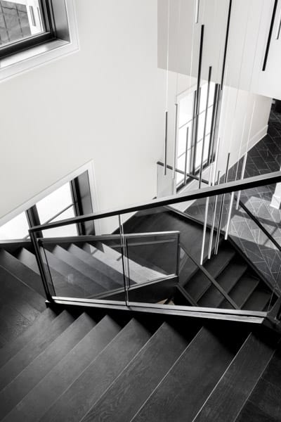 A black and white monochrome staircase with a handrail, balusters, and a window leading to a room in an indoor building.