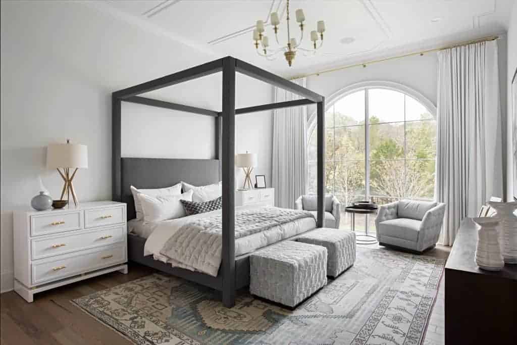 A boutique hotel bedroom is decorated with furniture, bedding, linens, window treatments, and throw pillows, creating a cozy and inviting interior design.